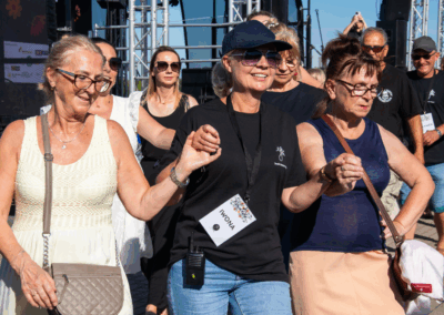 grupa os&oacute;b w średnim wieku trzymająca się za ręce, stoją n scenie